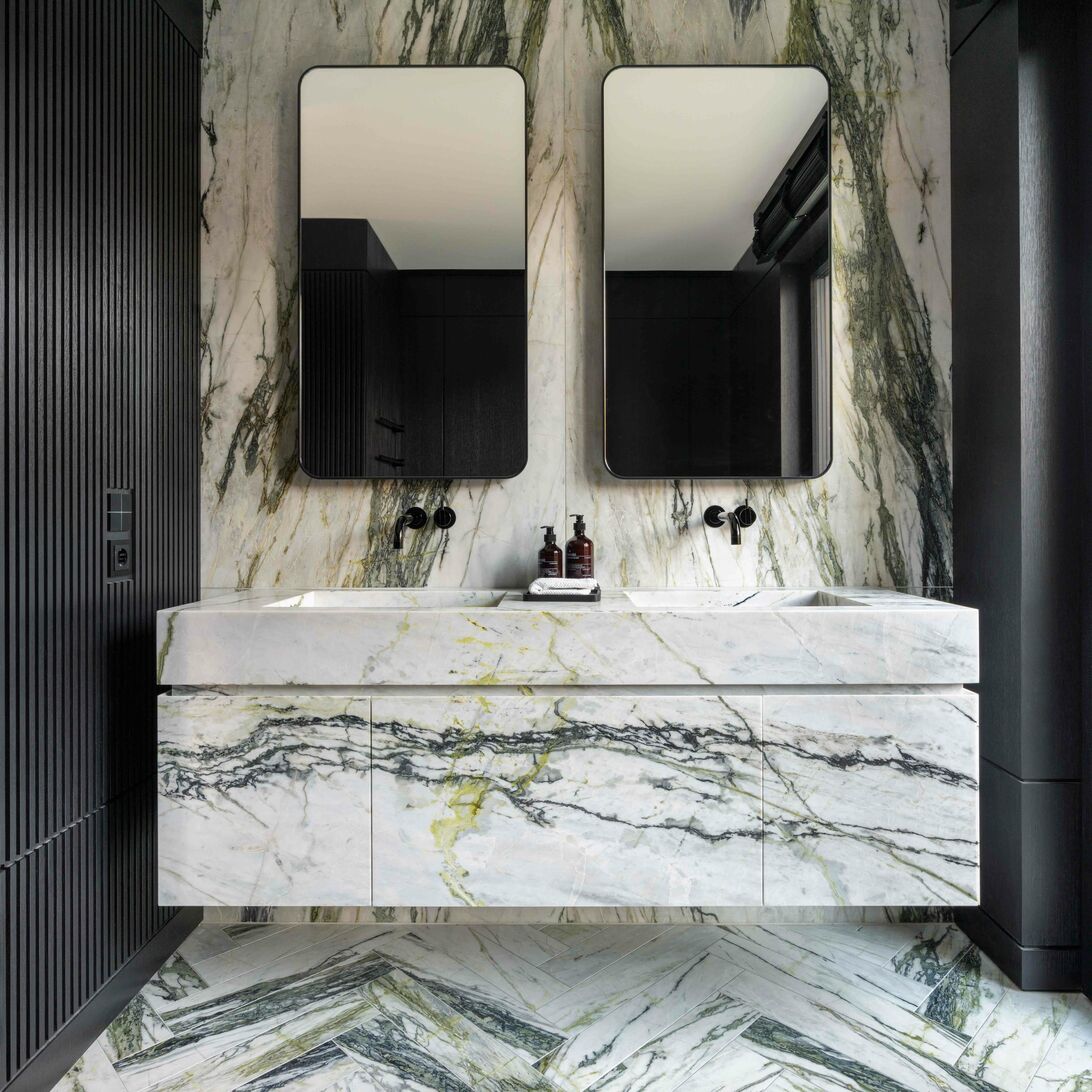 Modernes Badezimmer mit marmoriertem Waschtisch, zwei rechteckigen Spiegeln und schwarzen Armaturen. Elegante, nat&uuml;rliche Steinoptik dominiert den Raum.