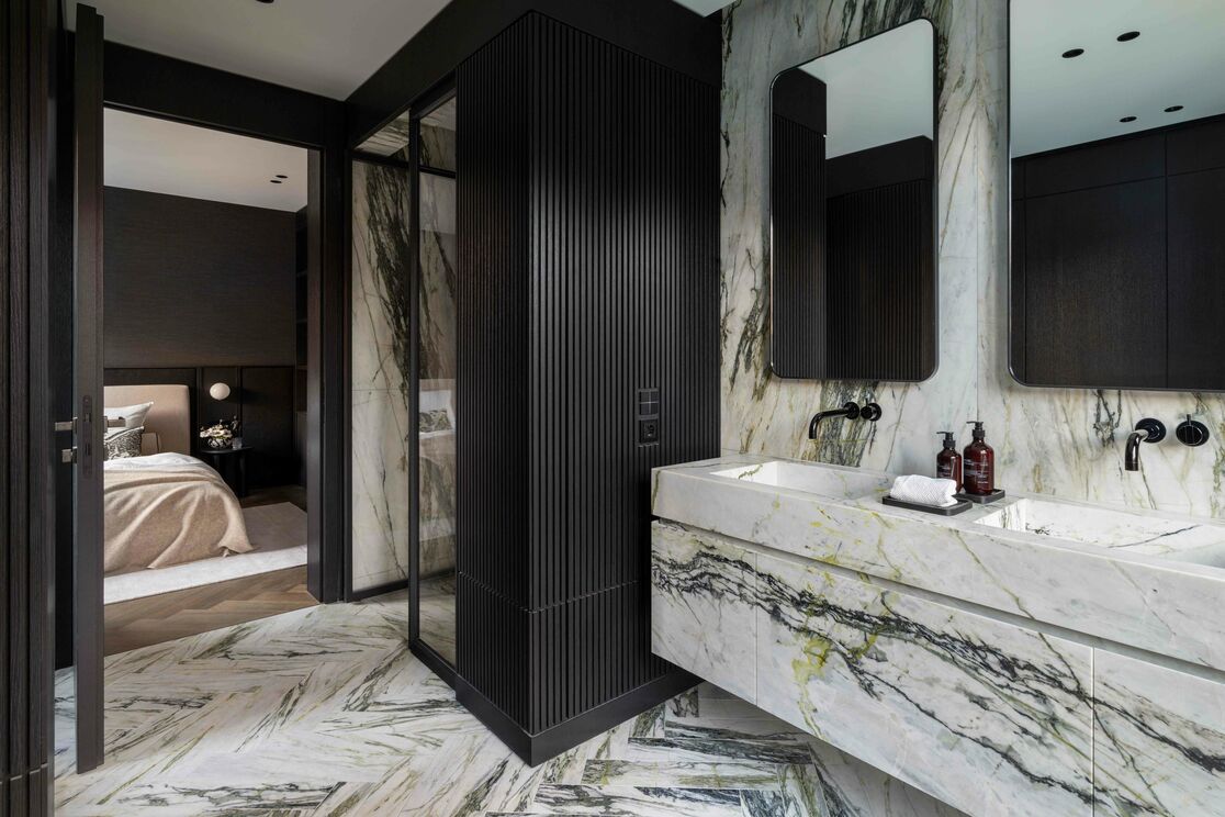Modernes Badezimmer mit marmorierten Oberflächen und Doppelwaschtisch. Schwarze Akzente und Armaturen, Glasduschtür, und ein Übergang zum Schlafzimmer schaffen ein harmonisches Design. Modernes Badezimmer mit marmorierten Oberflächen und Doppelwaschtisch. Schwarze Akzente und Armaturen, Glasduschtür, und ein Übergang zum Schlafzimmer schaffen ein harmonisches Design.