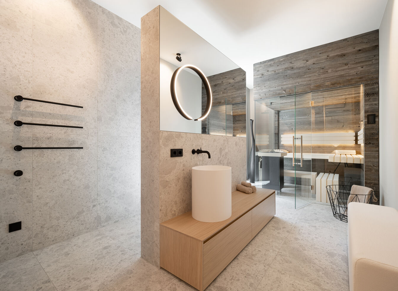Modernes Badezimmer mit rundem Spiegel, zylindrischem Waschbecken, Steinfliesen, Holzdetails und Glasdusche für eine stilvolle Atmosphäre. Modernes Badezimmer mit rundem Spiegel, zylindrischem Waschbecken, Steinfliesen, Holzdetails und Glasdusche für eine stilvolle Atmosphäre.